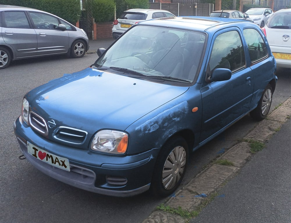 Picture of a battered blue Nissan Micra